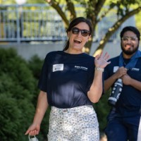 GVSU Alumni smile and wave towards camera and they walk to dorm building